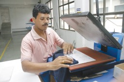 Operator putting label on a seamless garment using heat transfer machine at Precise Seamless Apparels